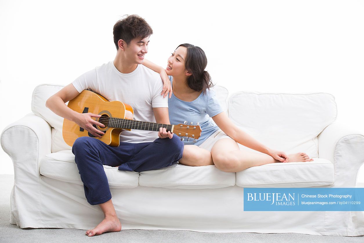 Young Chinese man playing guitar for his girlfriend