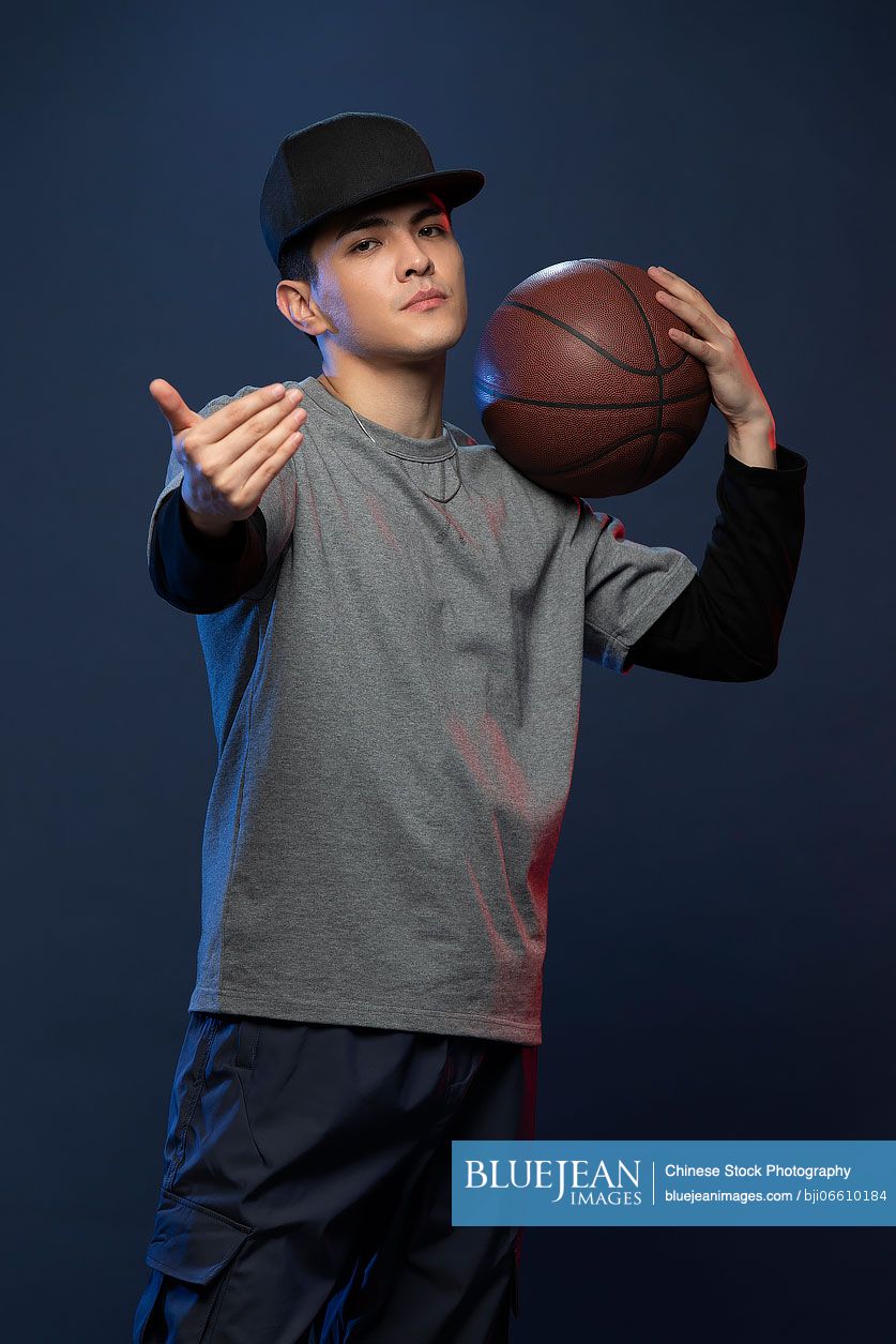 Studio shot of fashionable young Chinese man playing basketball