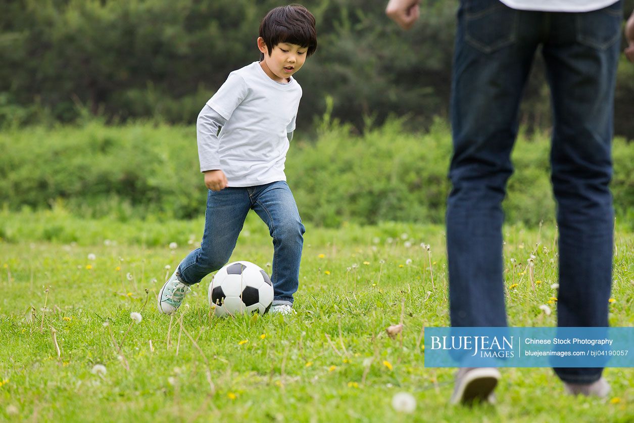 Happy Chinese father and son playing football together