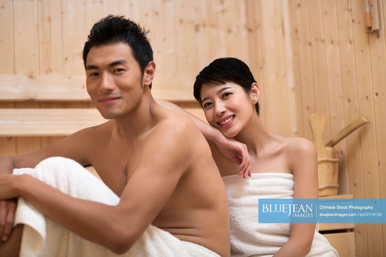 Happy young Chinese couple relaxing in sauna