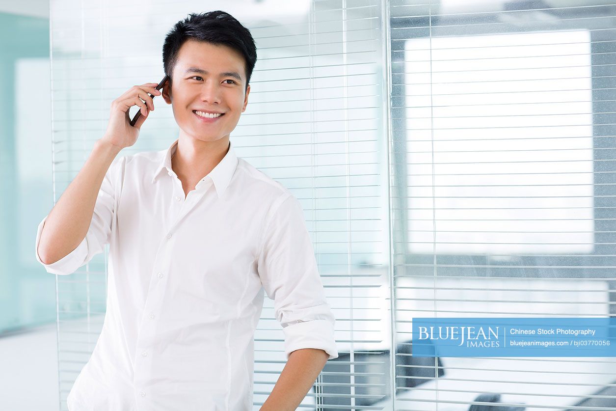 Young Chinese man on the phone in office