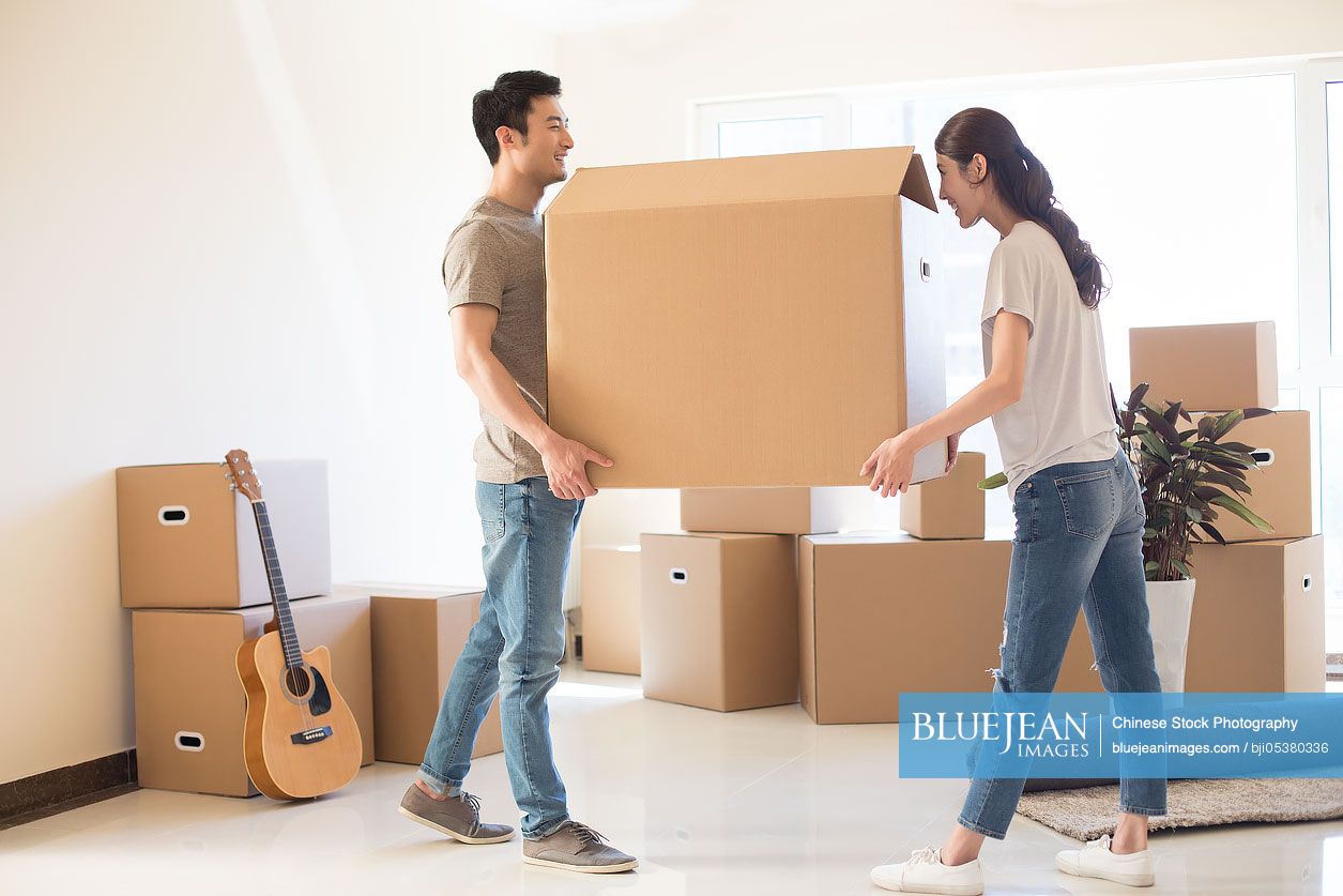 Happy young Chinese couple moving to a new house