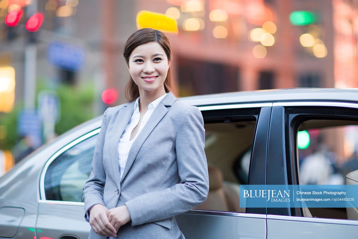 Chinese businesswoman standing next to the car