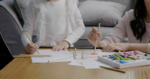 Little girl drawing with her mom by her side