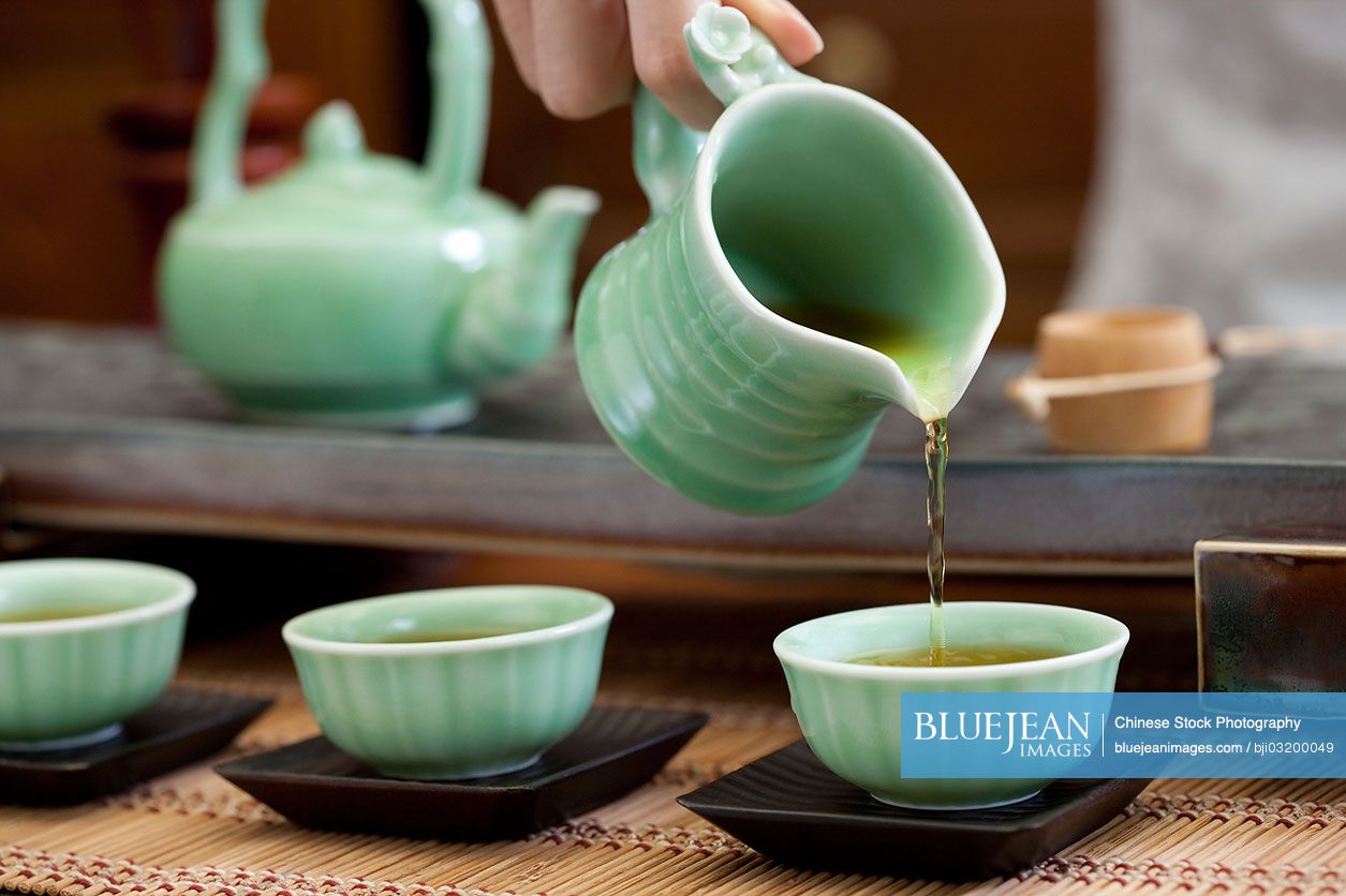 Female Chinese pouring tea into tea cups