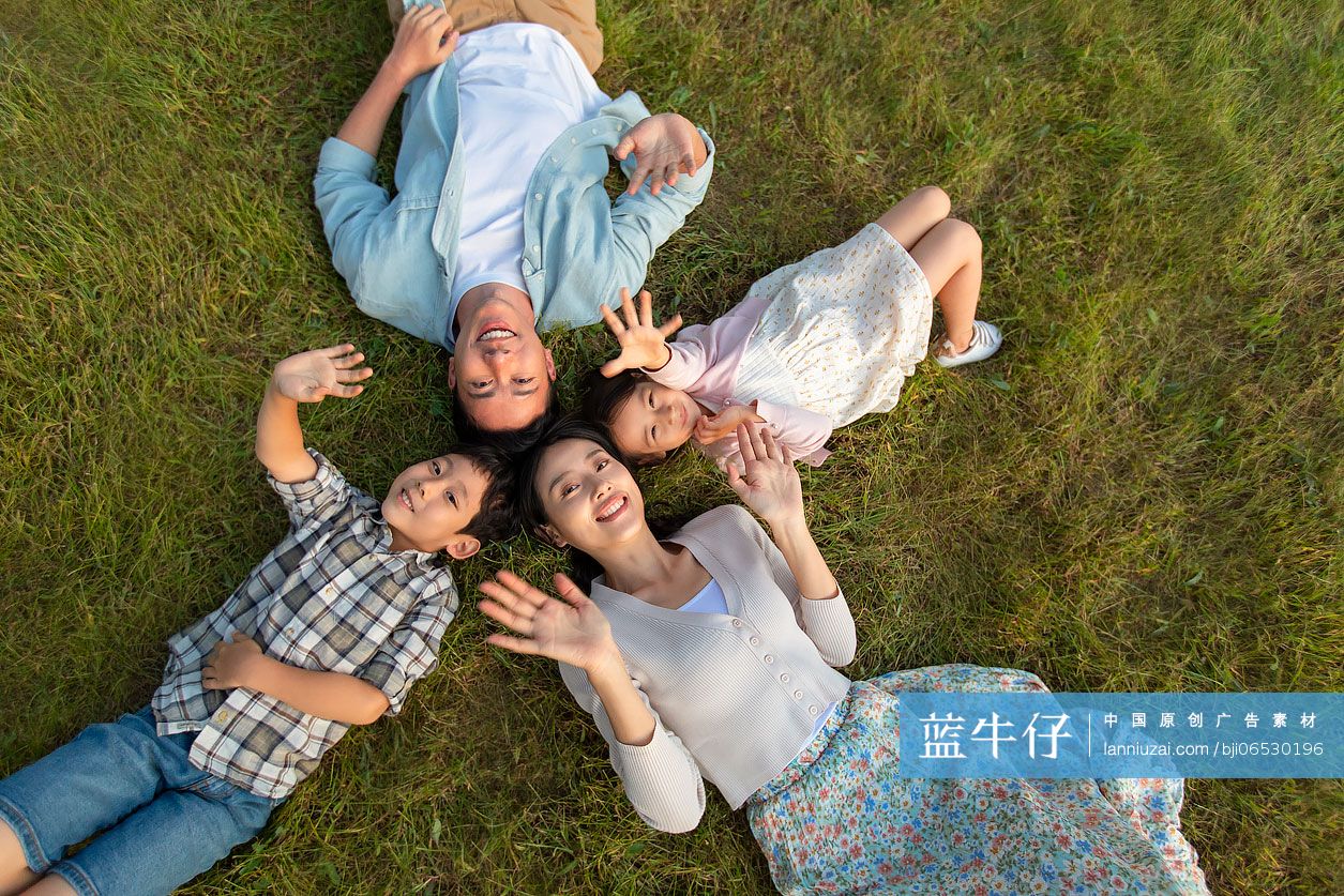 快乐的年轻家庭躺在草地上