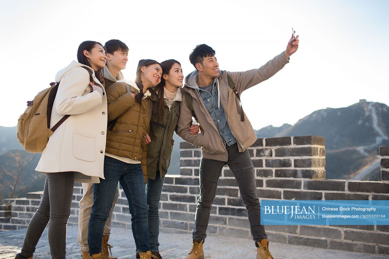 Happy young Chinese friends taking selfies on the Great Wall