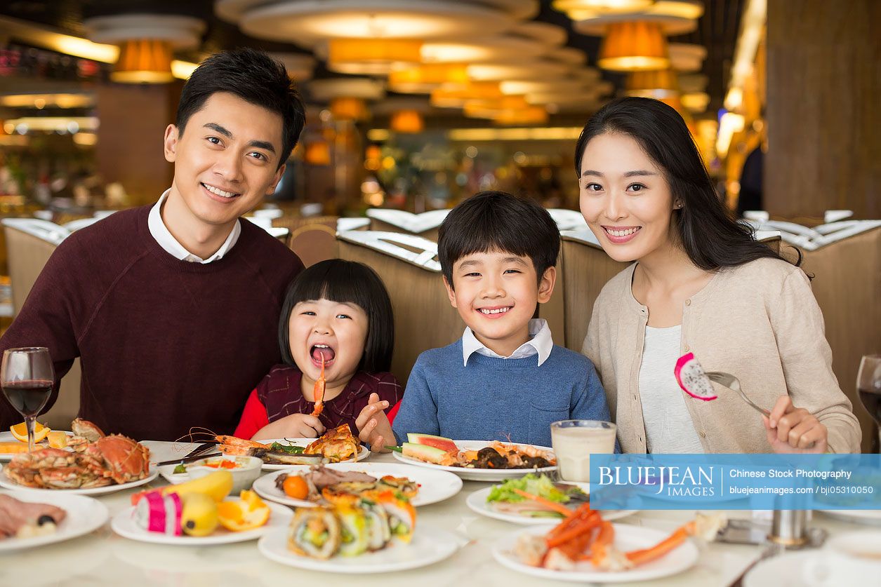 Cheerful young Chinese family having buffet dinner