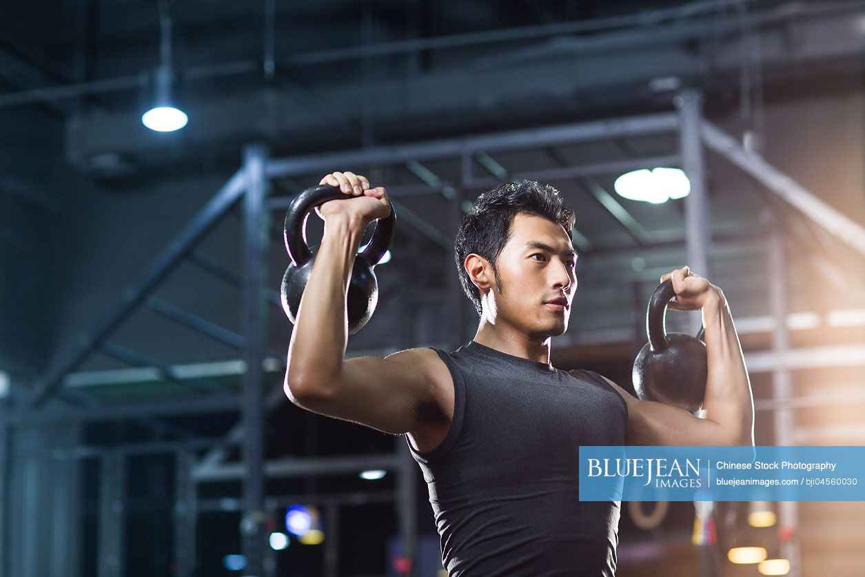 Young Chinese man training with kettlebells in crossfit gym