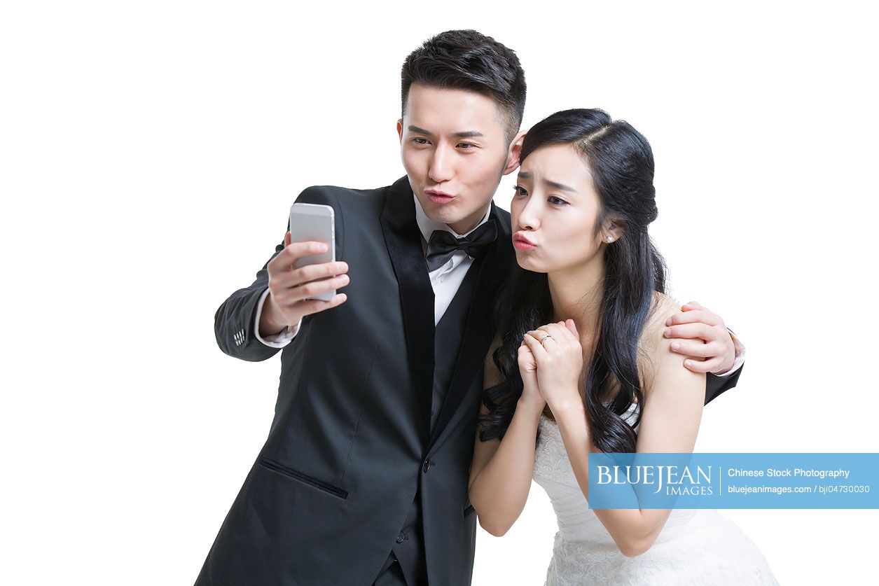 Happy Chinese bride and groom taking self portrait with smart phone