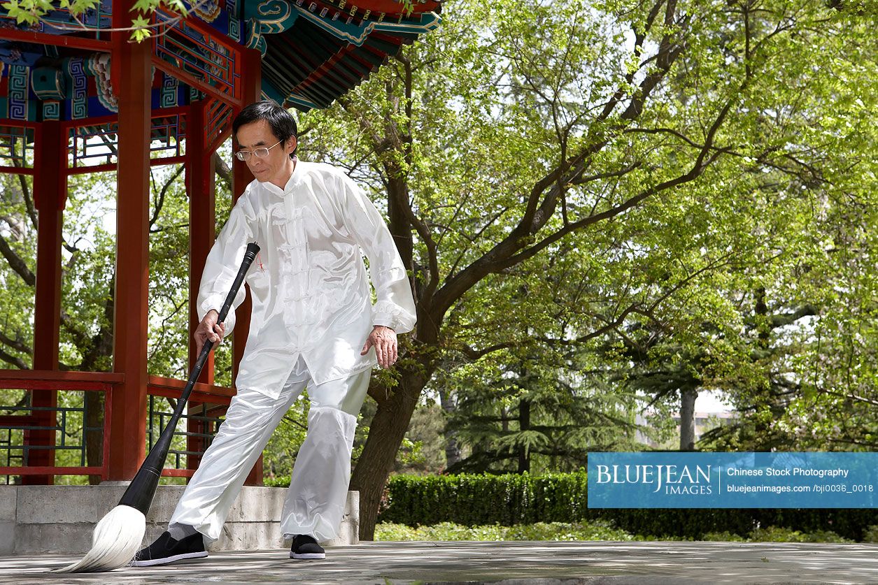 Chinese man practicing calligraphy in garden