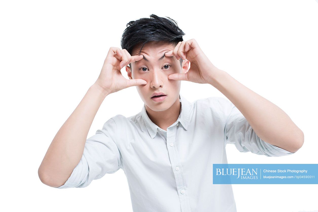 Tired Chinese man propping his eyes with hands