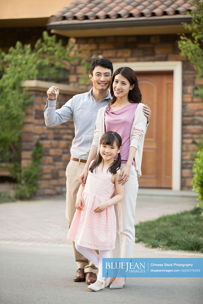 Happy young Chinese family holding keys to new house