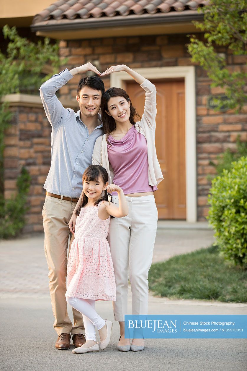 Happy young Chinese family holding keys to new house