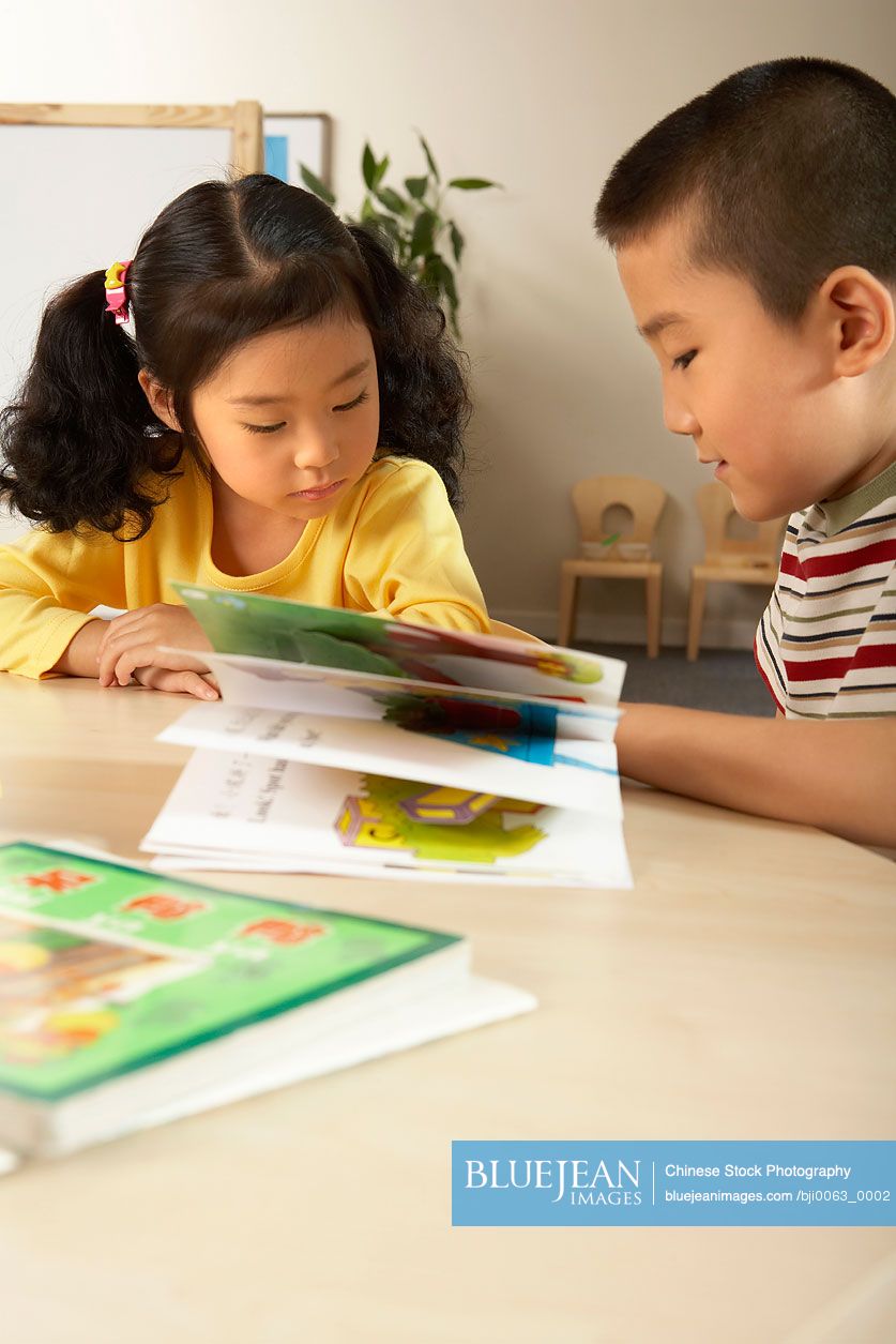 Young Chinese Children Reading A Book