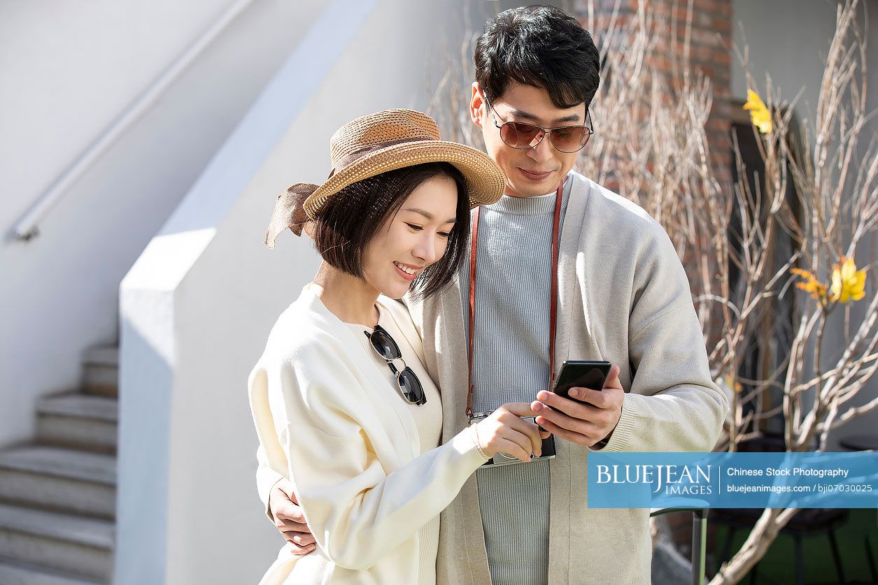 Happy young Chinese couple using smartphone