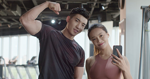 Young Chinese couple taking selfie with smartphone at gym,4K
