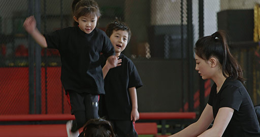 Active Chinese children having exercise class with their coach in gym,4K
