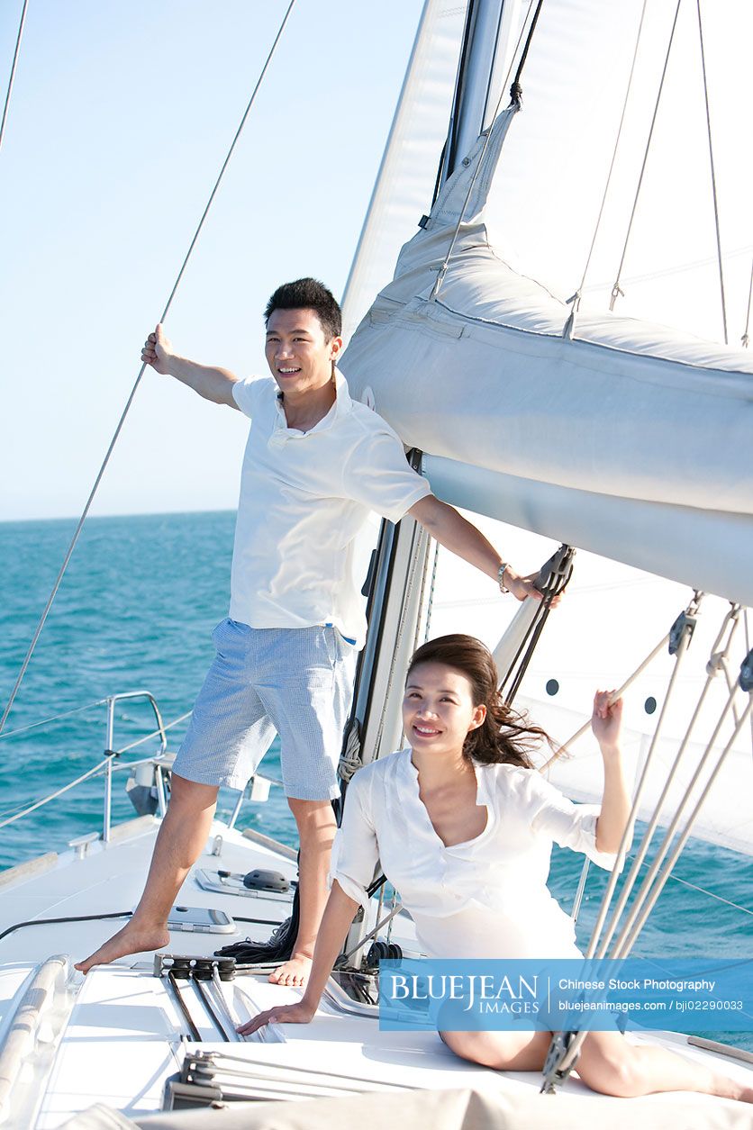 Happy young Chinese couple on a sailboat