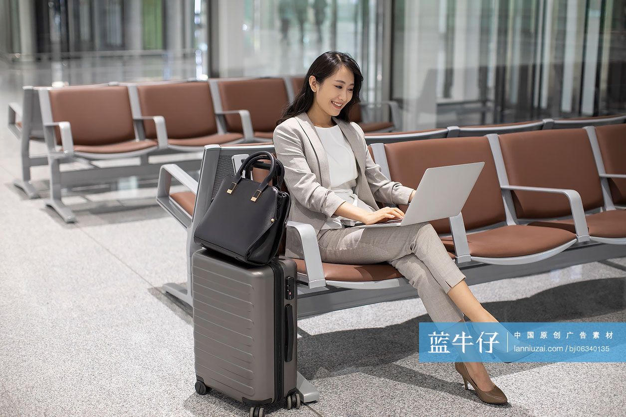 年轻商务女士在机场使用笔记本电脑