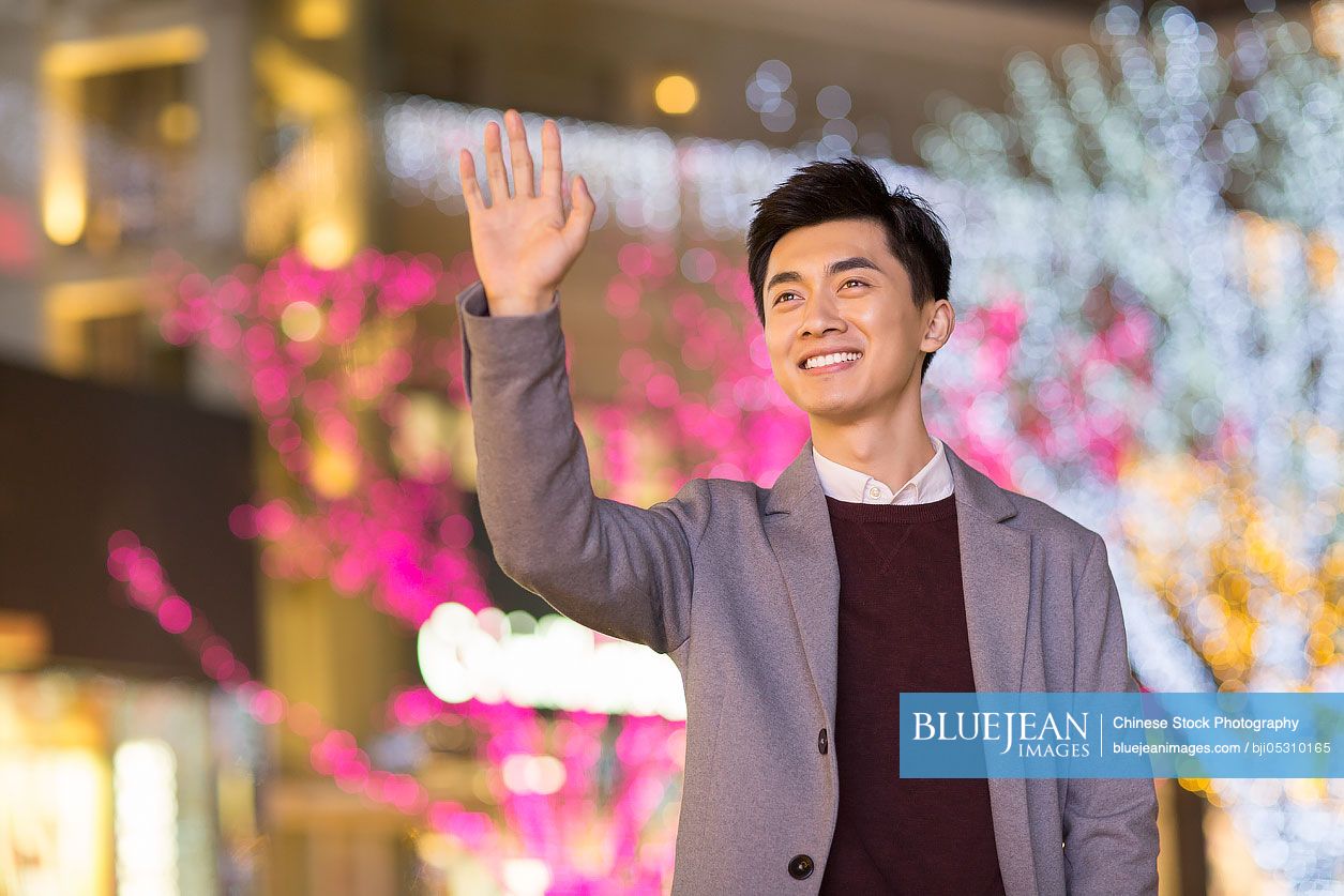 Cheerful young Chinese man waving