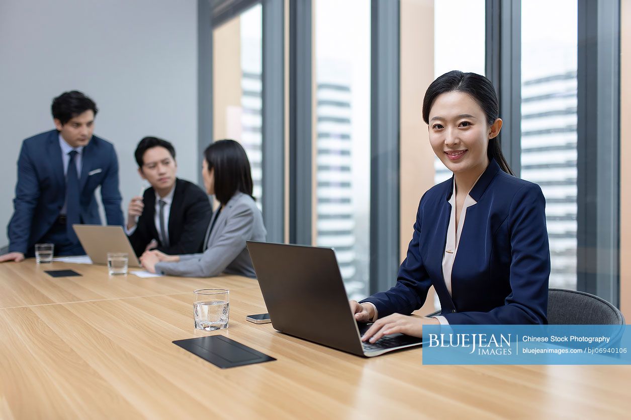 Young Chinese businesswoman using laptop in meeting room