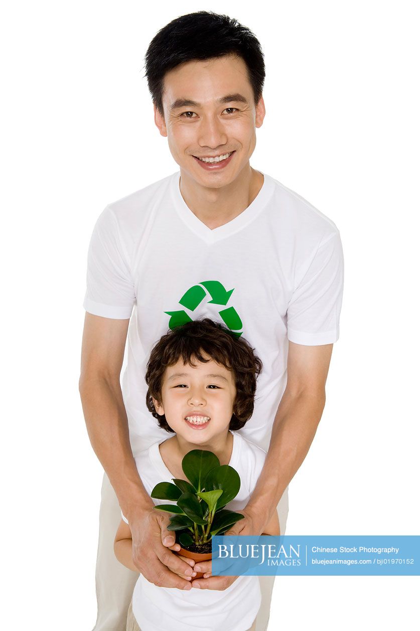 Little Chinese boy with his father holding a potted plant