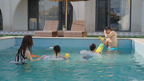 Happy family swimming and playing in the sparkling pool