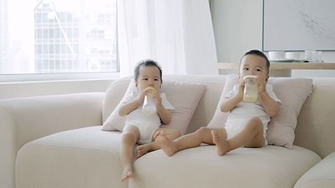 Two twin babies drinking formula from bottles.