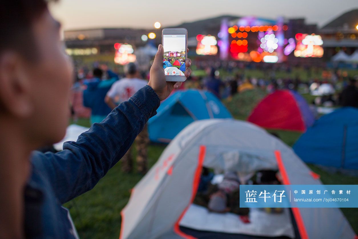 年轻男子在音乐节上用手机拍照