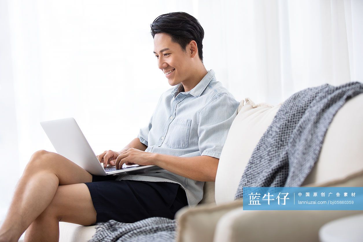 年轻男士在客厅使用笔记本电脑