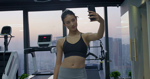 Young Chinese woman taking selfie with smartphone at gym,4K