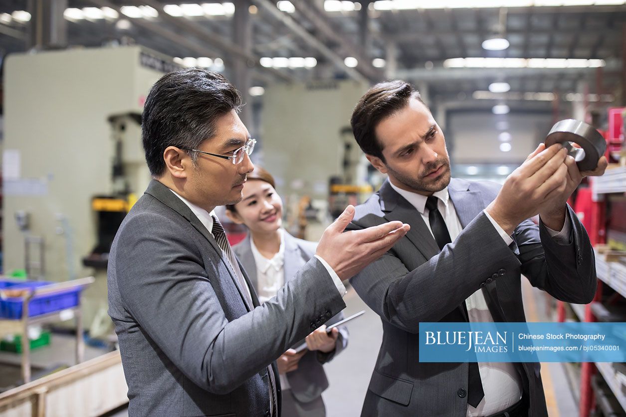 Business people checking machine parts in the factory