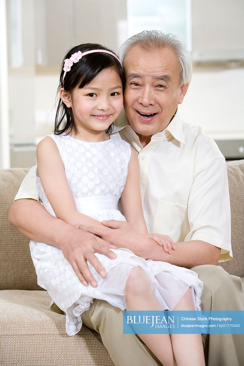 Portrait of Chinese grandfather and granddaughter at home