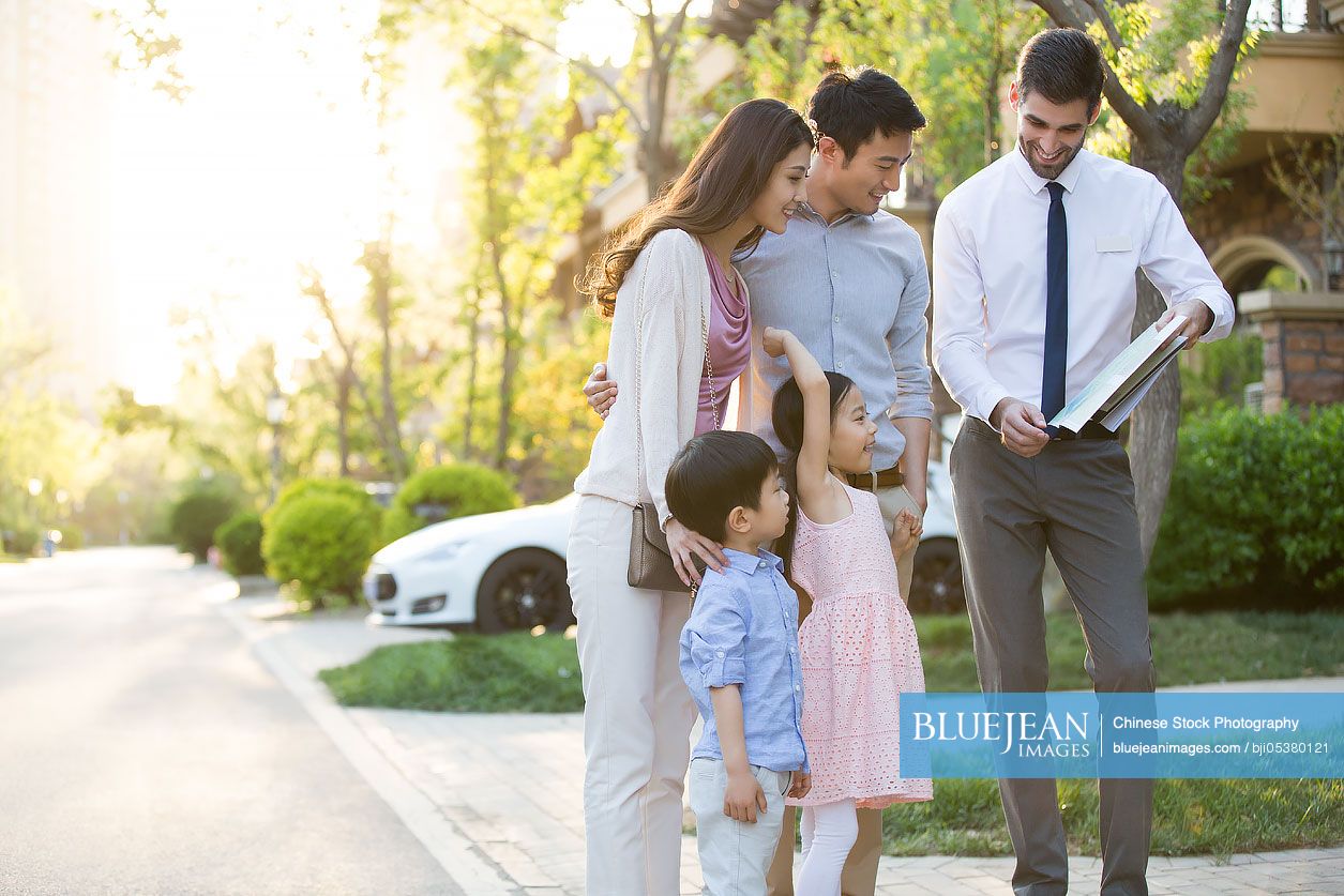 Happy young Chinese family and real estate agent