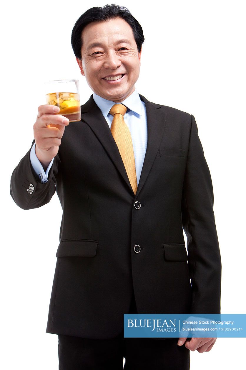 Senior Chinese businessman holding a glass of whiskey