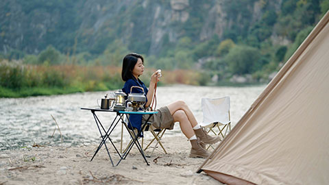 Happy young Chinese woman camping outdoors