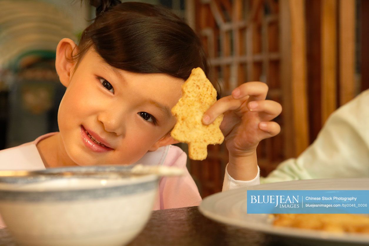 Chinese girl holding up Christmas tree shaped cookie