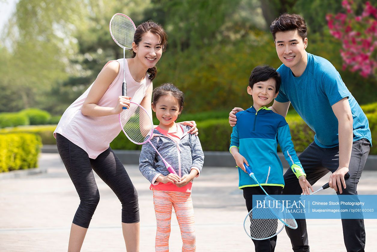 Happy young Chinese family playing badminton in park