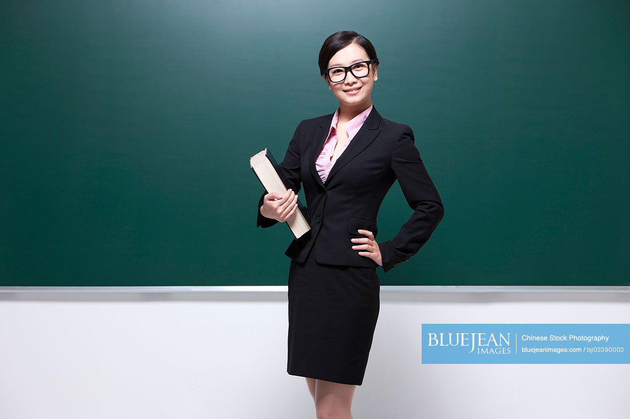 Professional female Chinese teacher hand on hip in classroom