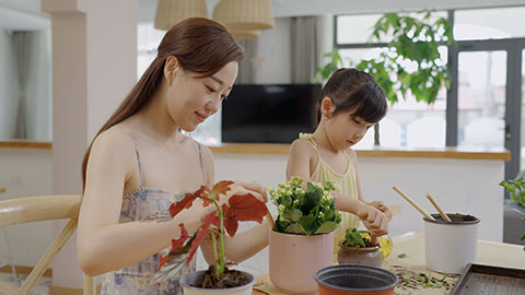 Mum and daughter enjoy potting plants together at home