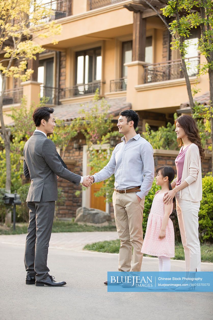 Happy young Chinese family shaking hands with realtor