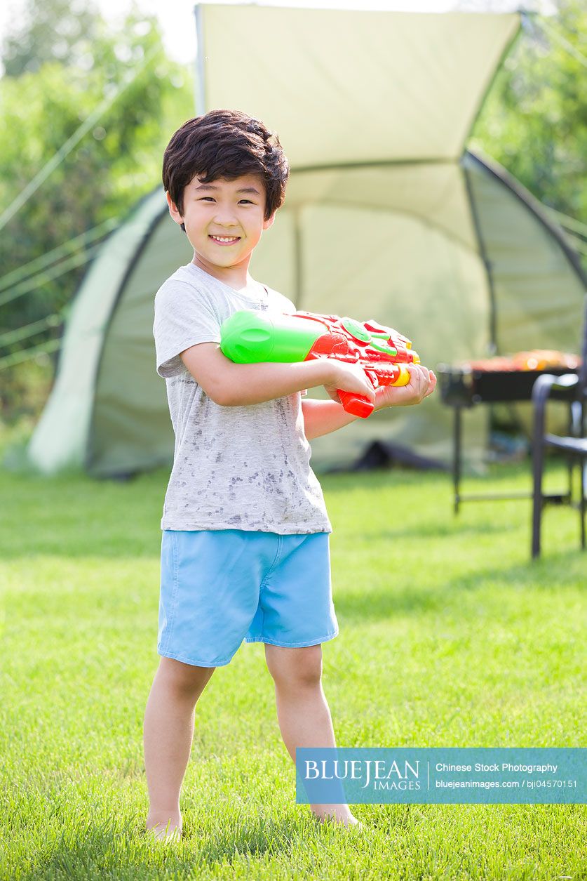 Happy Chinese boy holding a squirt gun