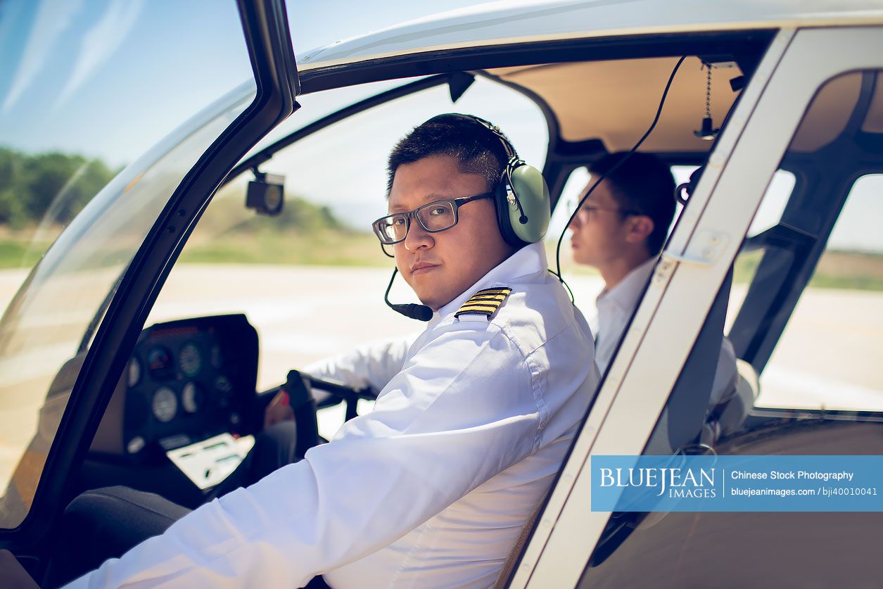 Chinese pilot teaching trainee to operate control panel in cockpit