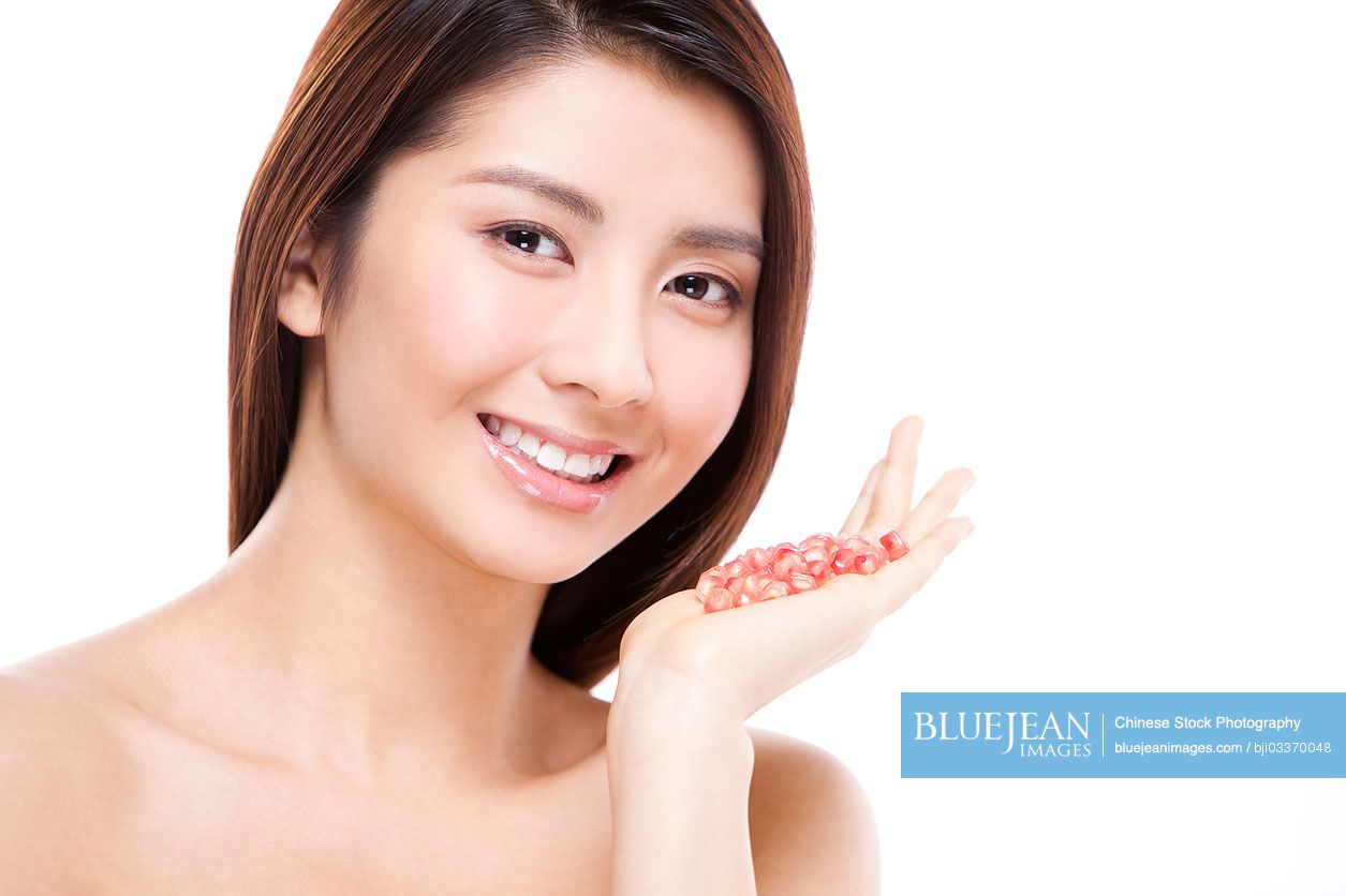 Charming young Chinese woman and pomegranate seeds