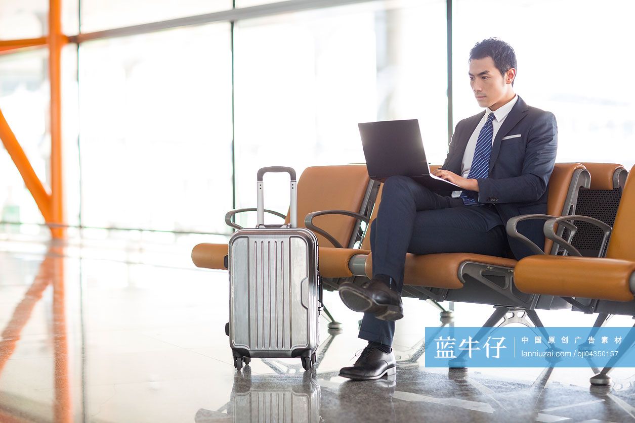 年轻商务男士在机场使用笔记本电脑