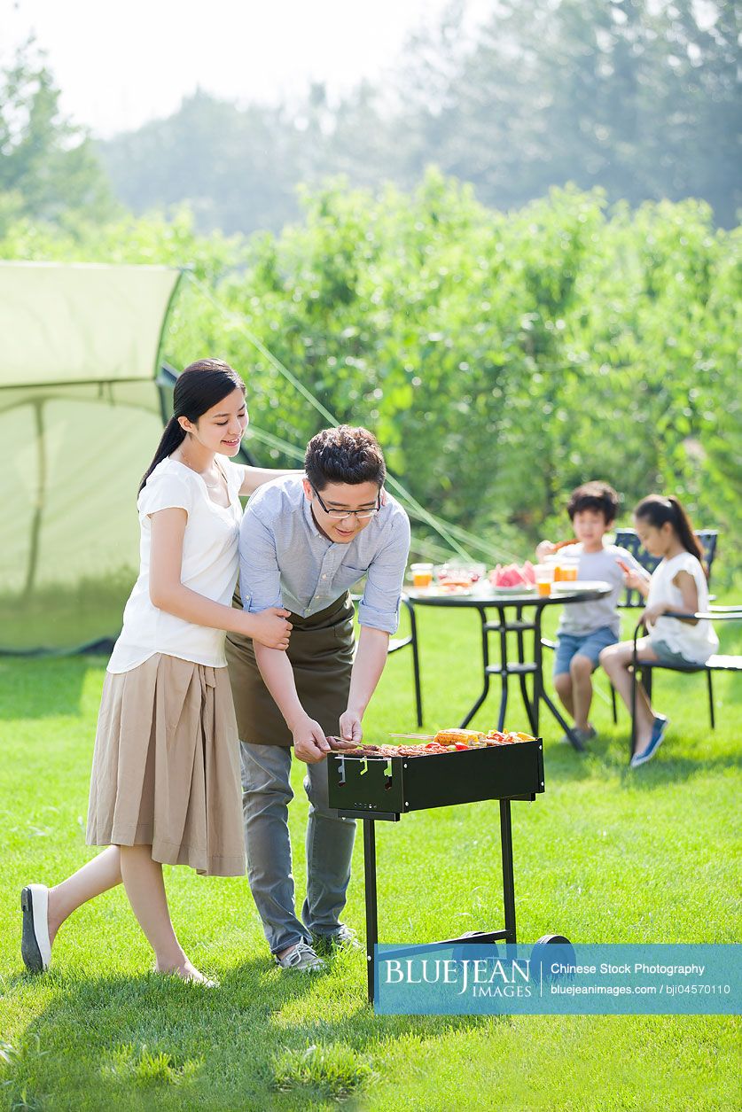 Young Chinese family barbecuing outdoors