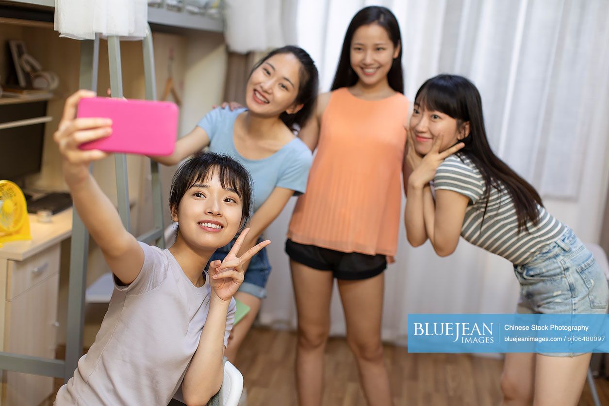 Young Chinese university students taking selfie in dormitory