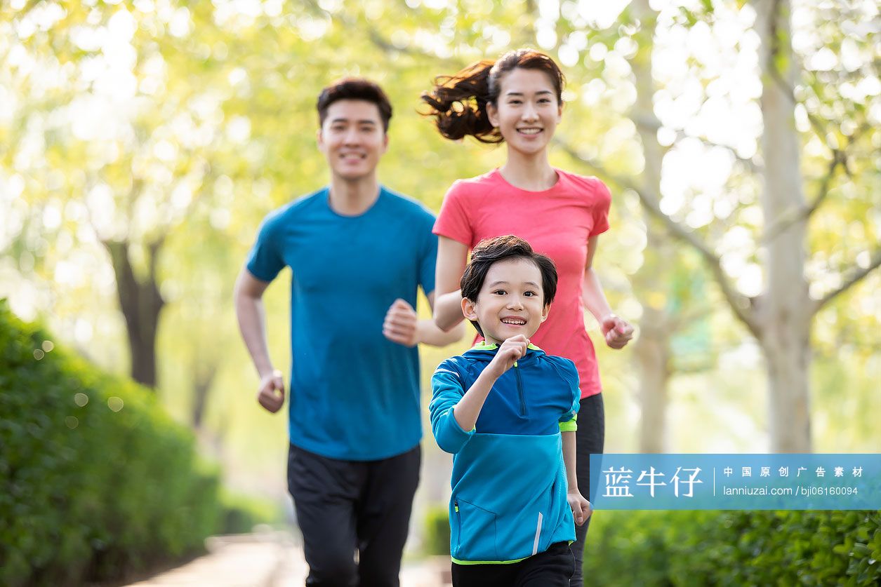 快乐的年轻家庭在公园跑步