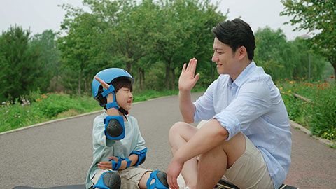 Dad assists his son with safety equipment before skateboarding